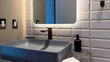 Une salle de bain moderne avec un lavabo rectangulaire, un miroir et une serviette posée sur le comptoir.
