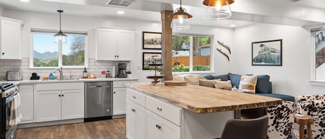 A modern kitchen with white cabinetry, a wooden island, and pendant lighting.