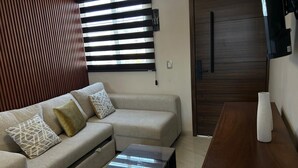 A modern living room with a sectional sofa, a coffee table, and a wooden dining table. - LESLIEES HOUSE (Zapopan)