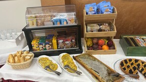 A buffet table with various food items including bread, pastries, and a honeycomb dessert. - Hotel Ristorante Il Melograno (Nuchis)
