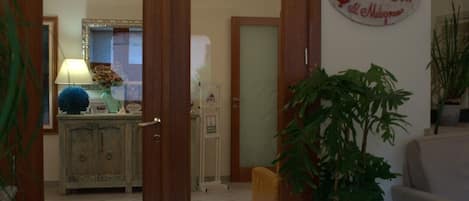 Habitación de hotel con puerta de madera, planta en maceta, sofá y cartel en la pared.