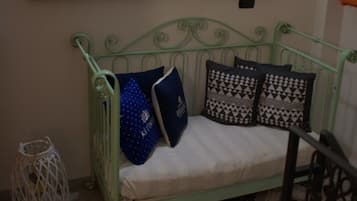 A room with a green metal bench, patterned floor tiles, a painting above the bench, and a wall-mounted light fixture.