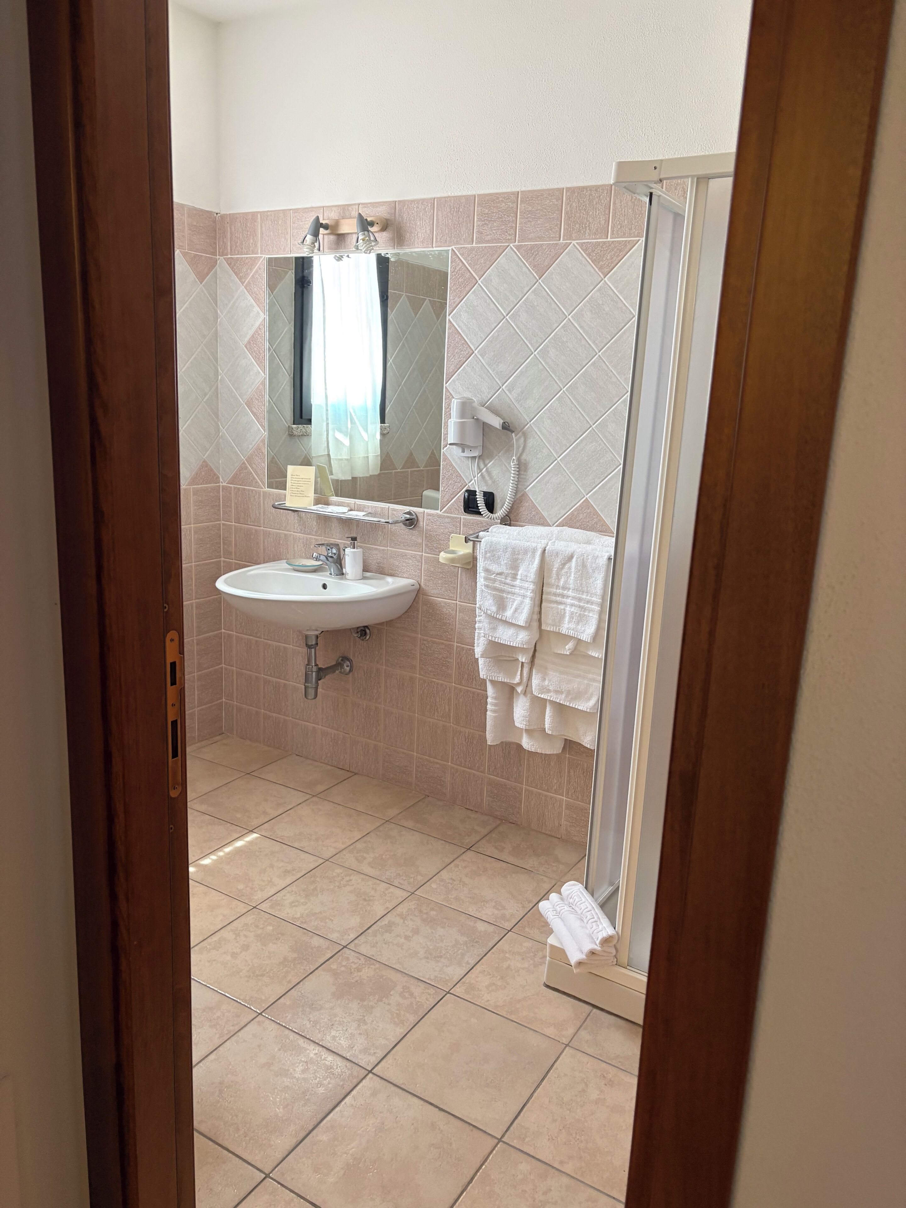 Een badkamer met een wastafel, spiegel, handdoekrek en douche.
