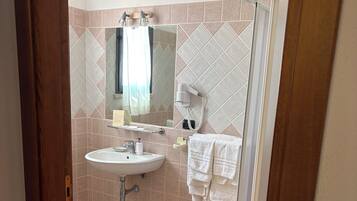 Een badkamer met een wastafel, spiegel, handdoekrek en douche.