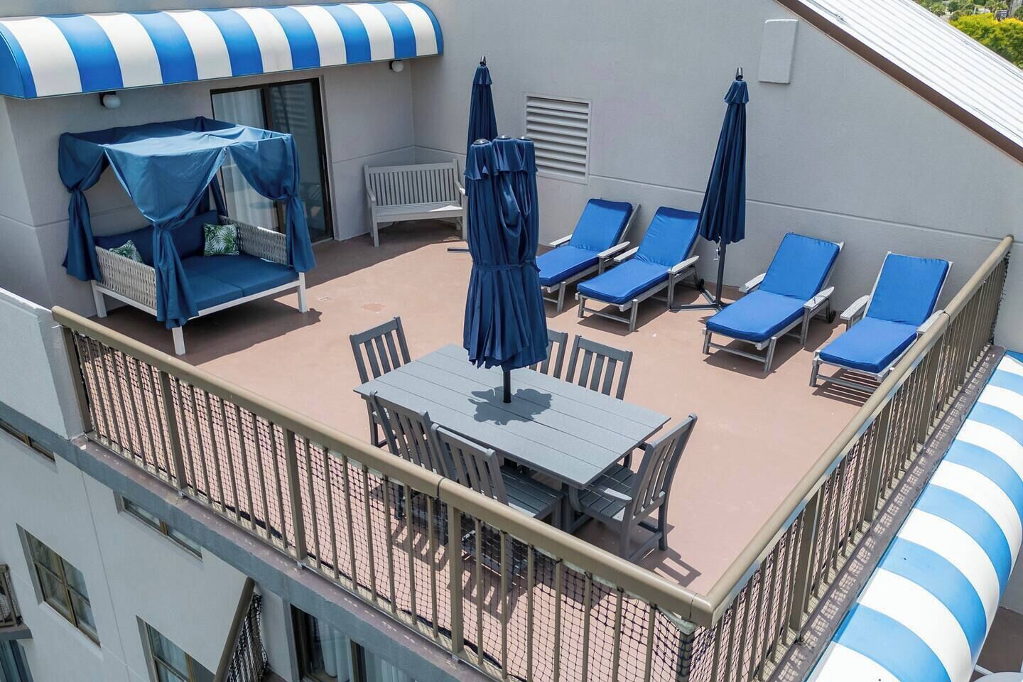 Une terrasse sur le toit avec une table et des chaises, des chaises longues avec des parasols et un espace salon couvert.
