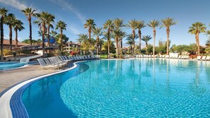 A large, clear swimming pool with lounge chairs and palm trees. - Coachella2ndWeek: Cozy 1-bedroom, 2 bed condo in Palm Desert:AC,resort amenities (Palm Desert)