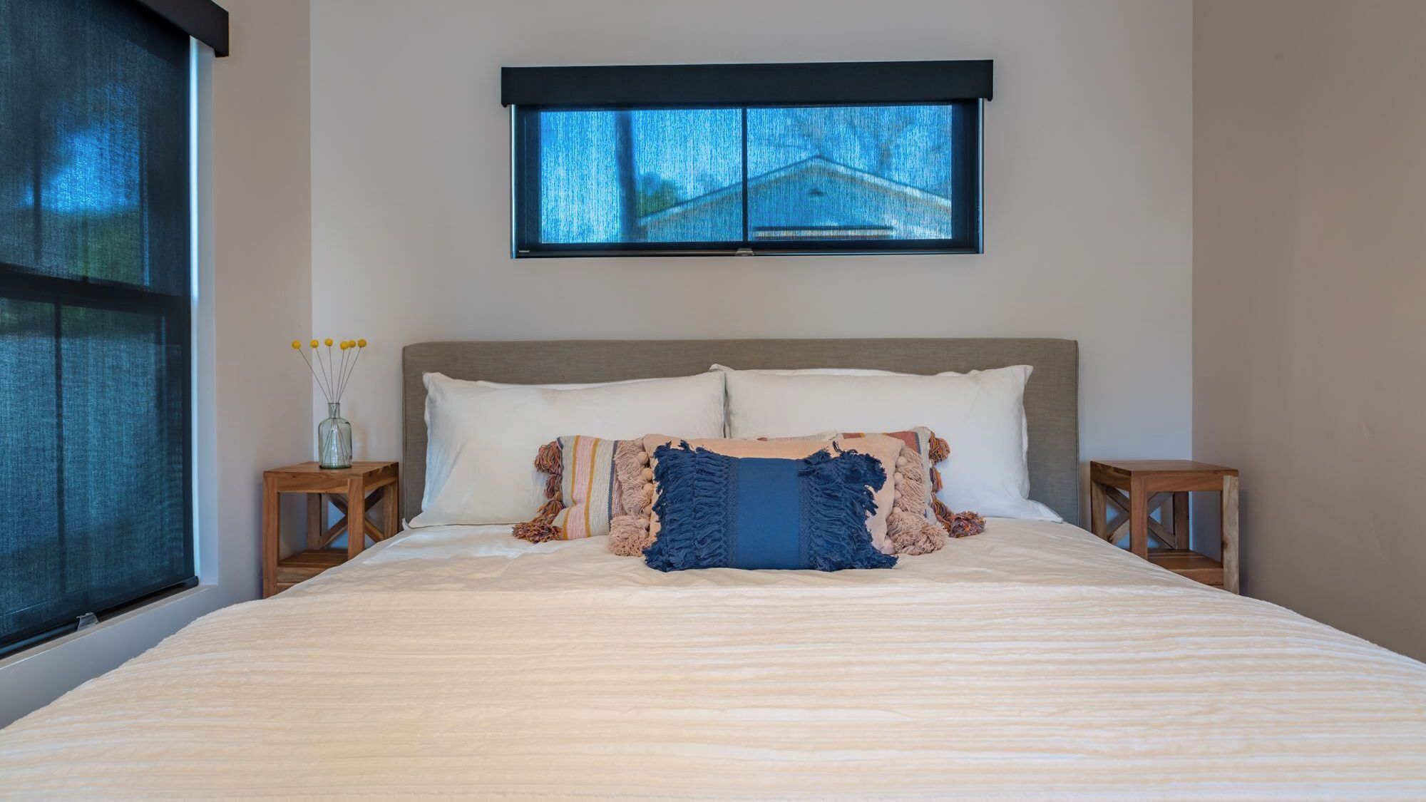 A bedroom with a large bed, a window, and two nightstands.
