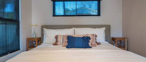 A bedroom with a large bed, a window, and two nightstands.