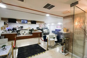 Eine Hotelhalle mit Empfangstresen, Sitzgelegenheit und einer Vitrine mit Flaschen.