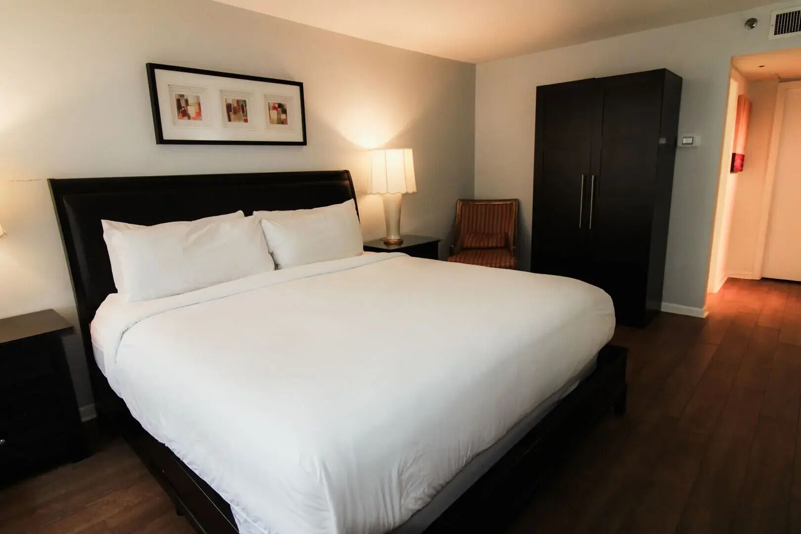 Cama bem arrumada com lençóis brancos em um quarto de hotel.