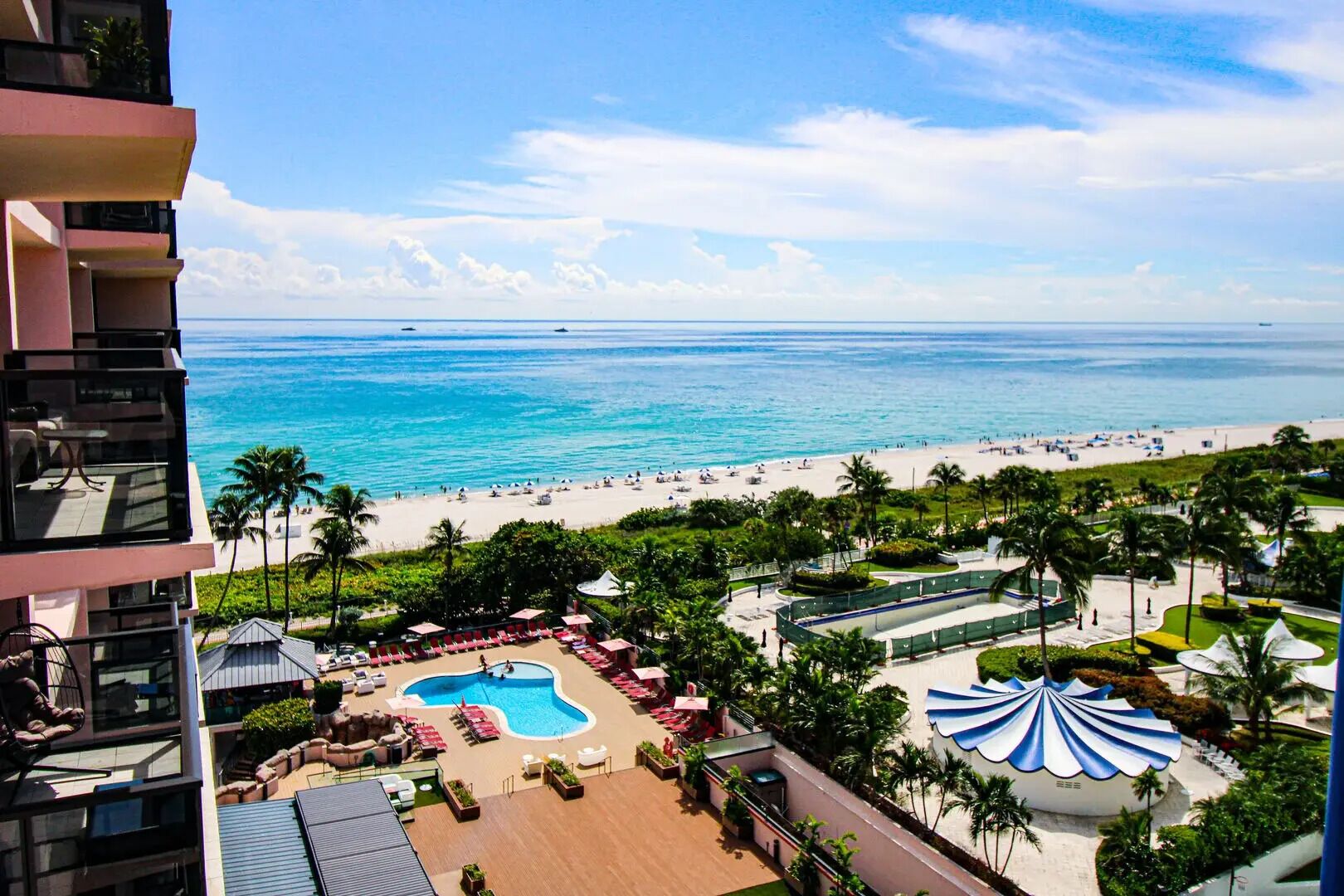 A resort with a pool, beach, and palm trees.