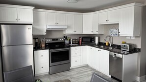 A modern kitchen with white cabinetry, stainless steel appliances, and a marble countertop.