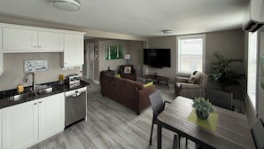 A modern apartment with a kitchen, living area, dining space, and a large window.