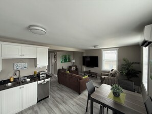 A modern apartment with a kitchen, living area, dining space, and a large window.