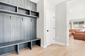 A modern interior with a grey built-in bench, a white door, and a living area with a brown sofa. - Peaceful|Hot Tub|Sauna|Close to Downtown (Castle Rock)