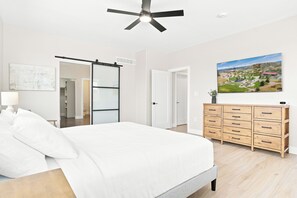 A bedroom with a bed, a dresser, a ceiling fan, a sliding door, and a painting on the wall. - Peaceful|Hot Tub|Sauna|Close to Downtown (Castle Rock)