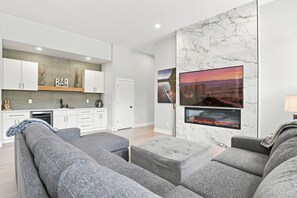 A modern living room with grey sofas, a flat-screen TV, and a fireplace. - Peaceful|Hot Tub|Sauna|Close to Downtown (Castle Rock)