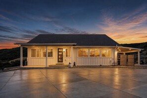 Ein zweistöckiges Haus mit überdachter Terrasse und Auffahrt.