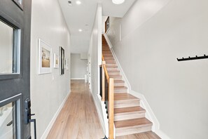 Ein Flur mit einer Holztreppe, weißen Wänden und gerahmten Bildern an der Wand.