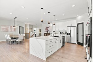 A modern kitchen with a marble island, pendant lighting, and stainless steel appliances.