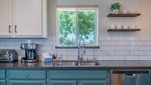 A kitchen with a stainless steel sink, a coffee maker, and a dishwasher.