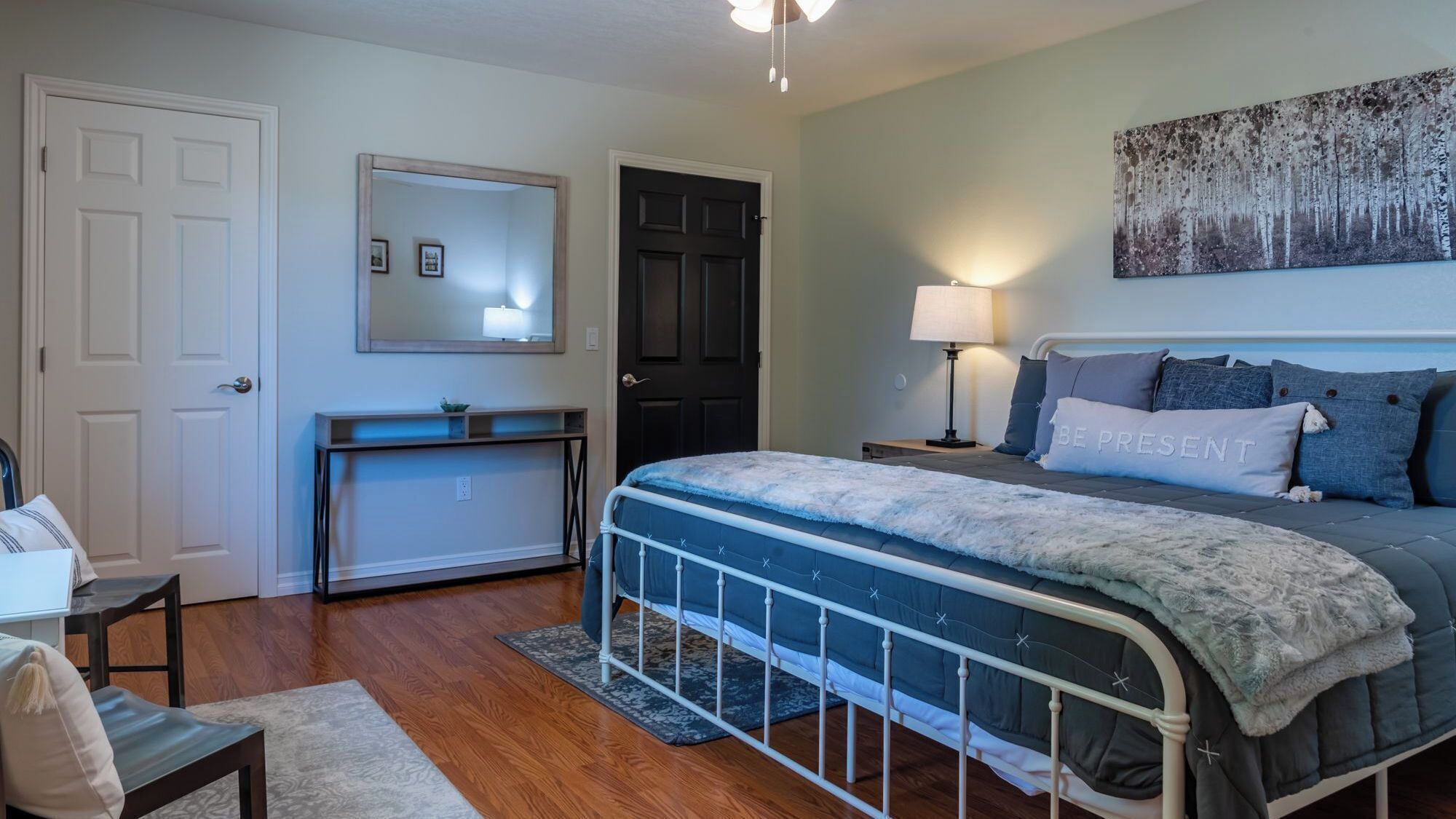 A bedroom with a bed, bedside table, lamp, and a painting on the wall.