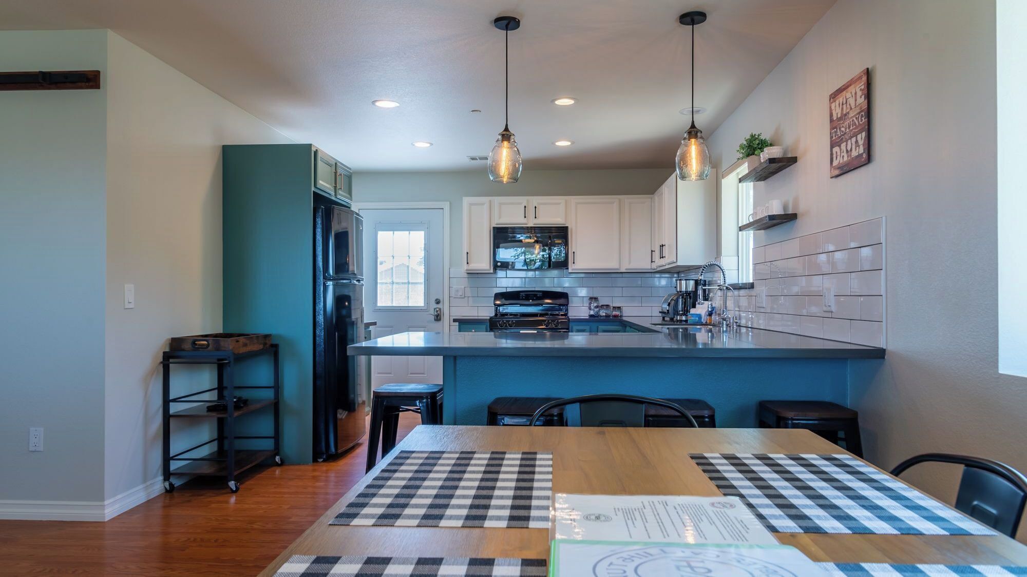 A modern kitchen with a central island, pendant lighting, and a view to the dining area.