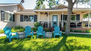 A two-story house with a porch, a satellite dish, and a tree in the front yard.