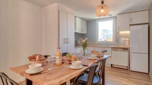 Une cuisine moderne avec une table à manger en bois, des meubles blancs et un four encastré.