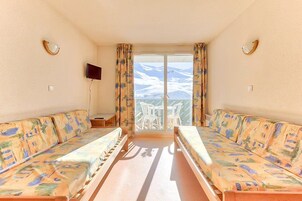 Habitación con dos sofás orientados hacia un balcón con vista a la montaña.