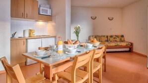 Une cuisine compacte comprenant une table à manger pour quatre personnes, un four à micro-ondes et un petit réfrigérateur.