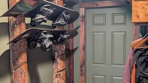 A room with a wooden door, a coat rack with clothes, and a skateboard hanging on a wooden structure. - Cabin with Private Pond - 61 Acres - Close to Gore (Johnsburg)