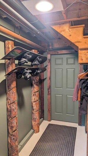 A room with a wooden door, a coat rack with clothes, and a skateboard hanging on a wooden structure. - Cabin with Private Pond - 61 Acres - Close to Gore (Johnsburg)