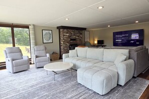 Un salon moderne comprenant un canapé d’angle, deux fauteuils, une table basse et un téléviseur à écran plat.