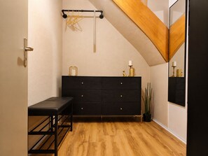 A room with a black dresser, a wooden bench, a hanging light fixture, and a potted plant. - Quiet & Cozy Studio Near the Heath (Schneverdingen)