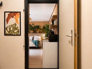 A doorway leading to a bedroom with a bed, bedside table, and a radiator. - Quiet & Cozy Studio Near the Heath (Schneverdingen)
