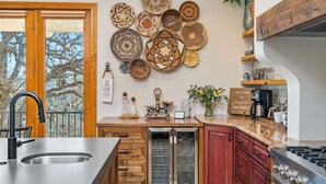 Una cocina con un lavaplatos de acero inoxidable, armarios de madera, horno empotrado y una variedad de platos decorativos en la pared.