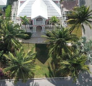 A large building with a symmetrical facade, a central entrance with a decorative arch, and a surrounding lawn with palm trees. - Paradise Villa - 3BR / 3BA w/ Boat Slip in February Point (George Town)