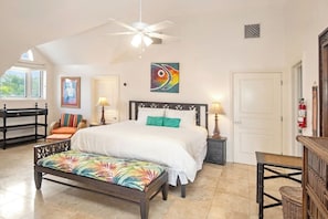 A bedroom with a bed, a bench, a chair, a ceiling fan, and a painting on the wall. - Paradise Villa - 3BR / 3BA w/ Boat Slip in February Point (George Town)