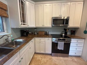 A kitchen with white cabinets, a stainless steel sink, a microwave, and an oven. - Paradise Villa - 3BR / 3BA w/ Boat Slip in February Point (George Town)