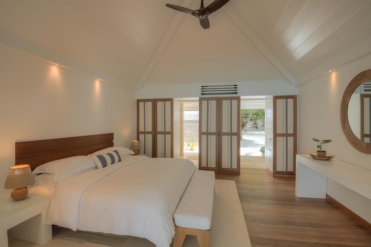 A bedroom with a bed, bedside tables, a ceiling fan, and a view of the outdoors.