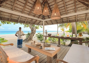 A beachside gazebo with a wooden table, chairs, and hanging lights. - Diamonds Athuruga Maldives Resort and SPA (Athuruga Island)