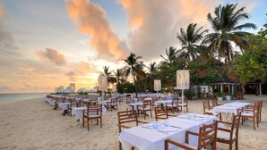 A beachside dining area with tables and chairs set up for guests. - Diamonds Athuruga Maldives Resort and SPA (Athuruga Island)