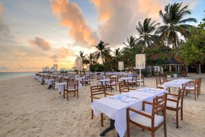 A beachside dining area with tables and chairs set up for guests.
