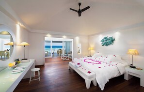A hotel room with a bed, a desk, a chair, and a view of the sea.