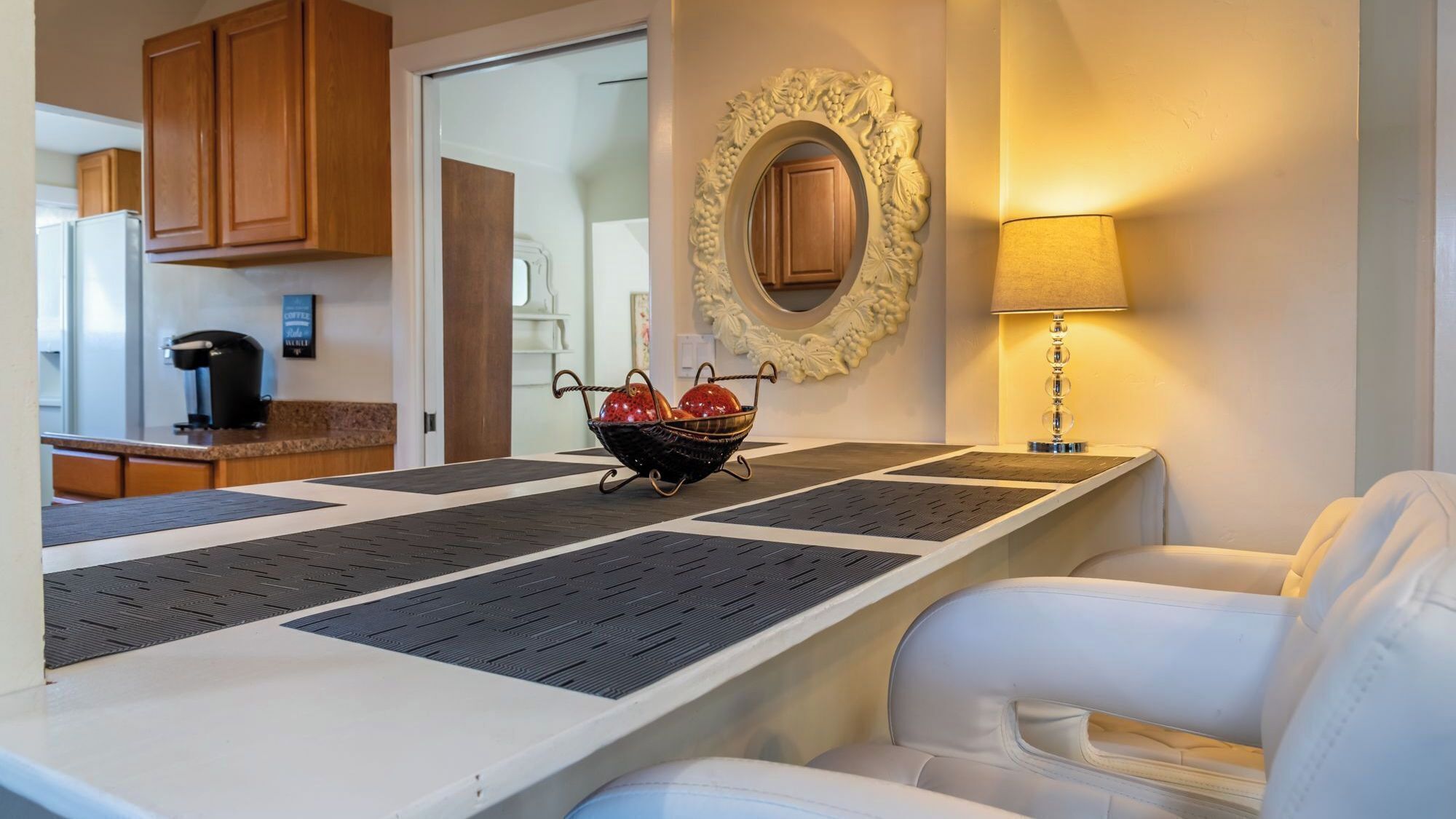 A modern kitchen with wooden cabinets, a coffee machine, and a decorative wall mirror.