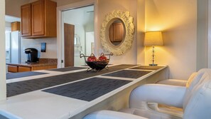 A modern kitchen with wooden cabinets, a coffee machine, and a decorative wall mirror.