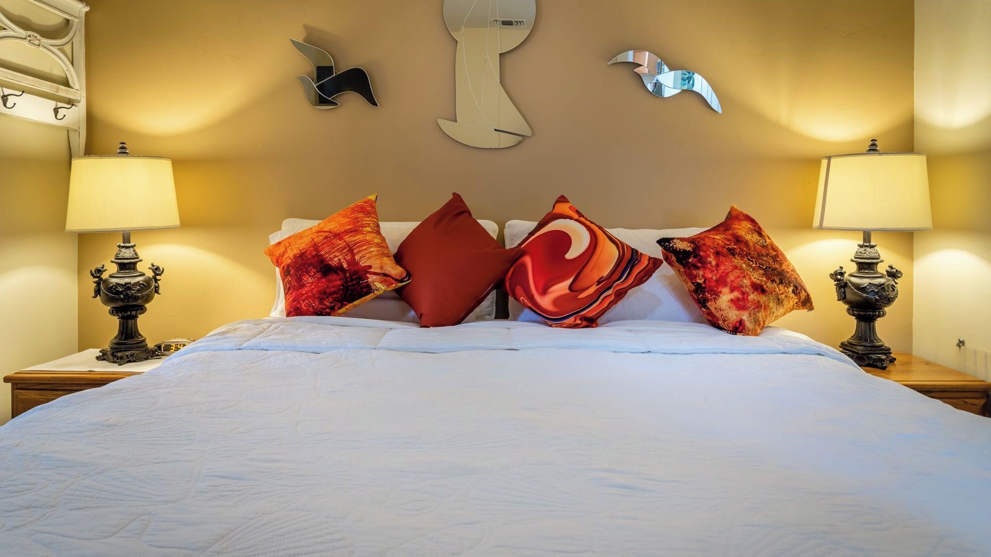 A hotel room with a large bed, decorative pillows, wall art, and bedside lamps.