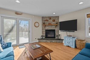 Ein Wohnzimmer mit Kamin aus Stein, einem Flachbildfernseher und einem blauen Sofa.