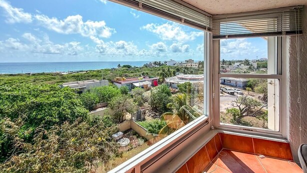 Quarto com vista para a paisagem costeira, incluindo edifícios e vegetação.